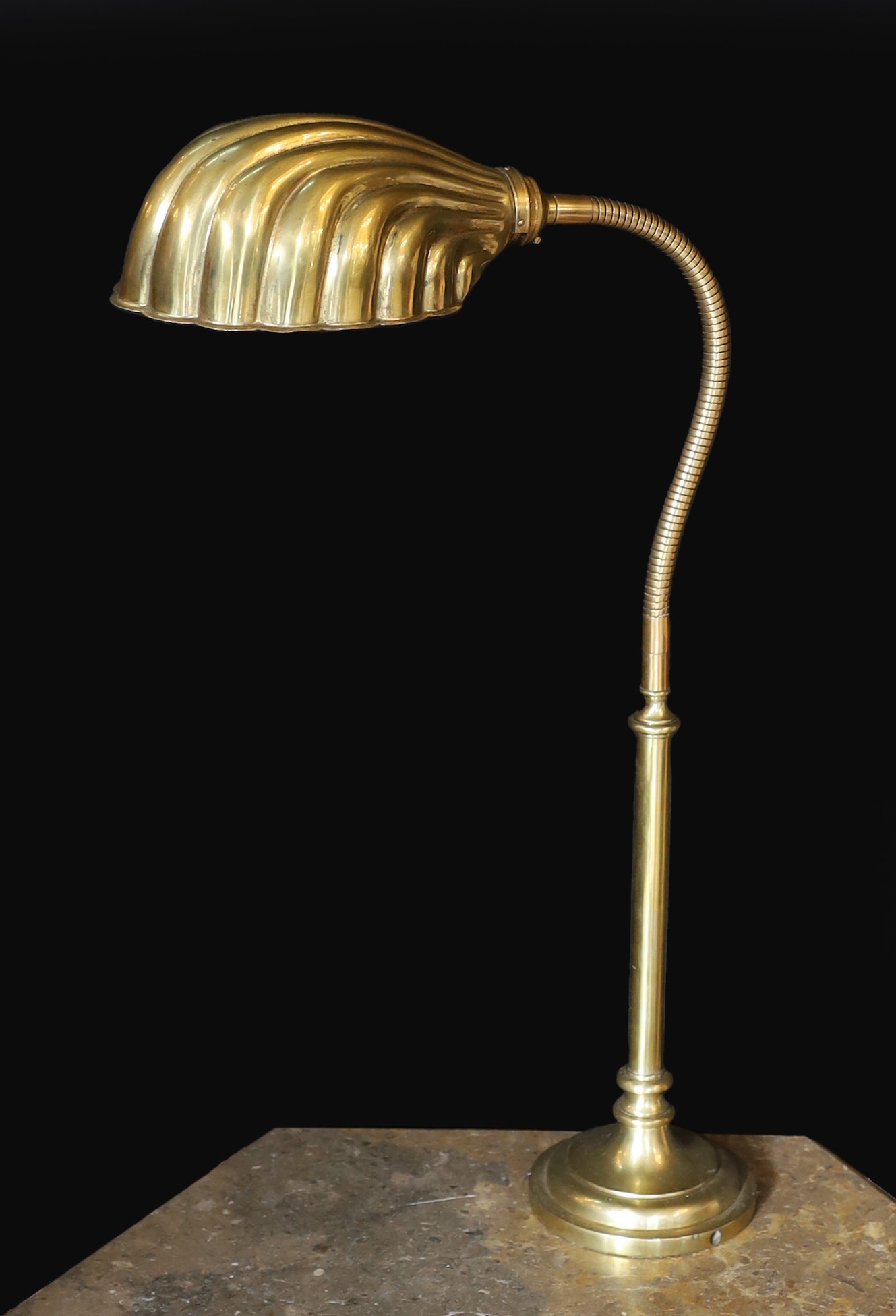 A 1930s English brass adjustable desk lamp, with flexible stem and scalloped shaped shade, height 58cm